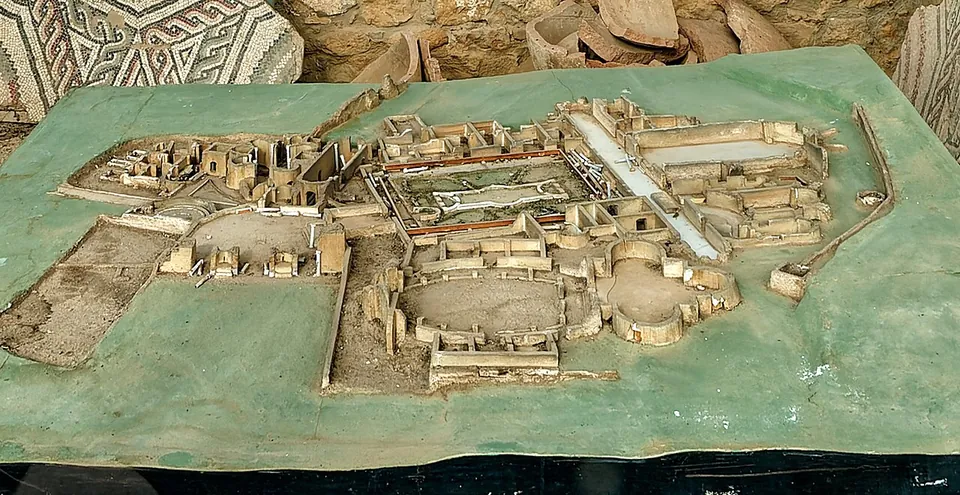 A scale model of the villa on a green base, showing its rooms grouped round a rectangular colonnaded courtyard, with a long corridor along one side and curved courtyards and apsed halls beyond.