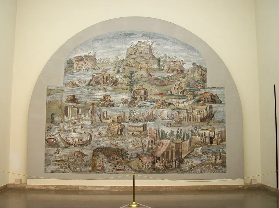 A very large mosaic with an arched top, mounted on a museum wall, showing a crowded landscape of water, rocky hills, buildings, boats and animals in faded colours.