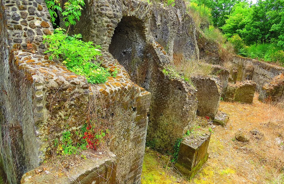 Close view of a wall face of small square grey stones set diagonally in a net pattern, framed by courses of thin red brick, with ivy at one edge.