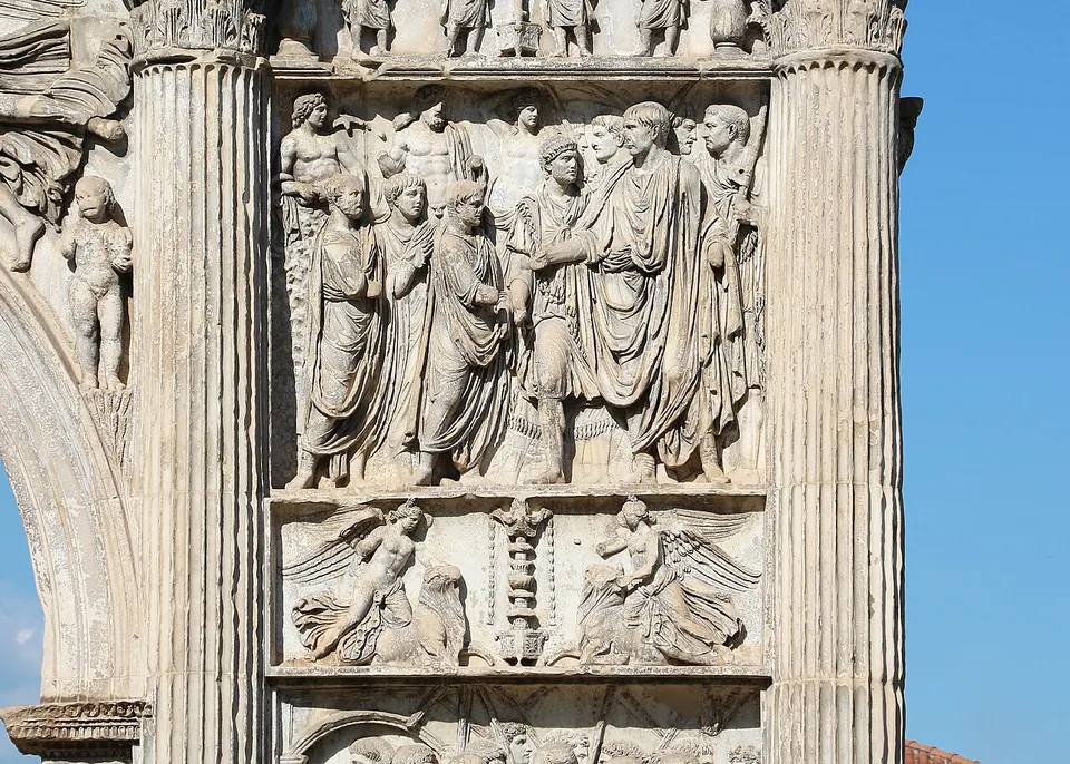 A close view of one pier, a tall relief panel of robed men standing in a crowd, framed by fluted columns, above a narrower panel with two winged figures either side of a tall ornament.