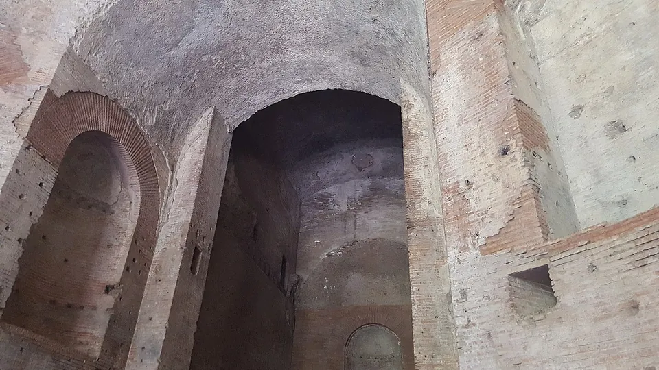 Close view of Roman brickwork, a deep arched recess between two smaller round-headed niches, the brick faces pitted with holes.