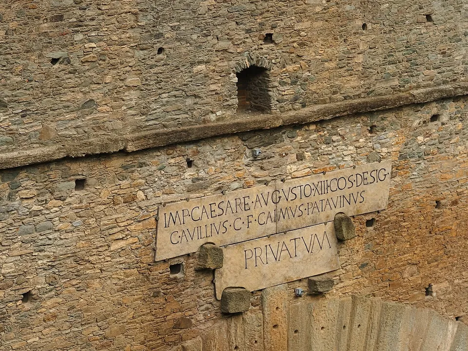 A pale stone tablet set into the rubble wall of the bridge, carved in Roman capitals across two lines, with the single word PRIVATVM on a smaller panel below.