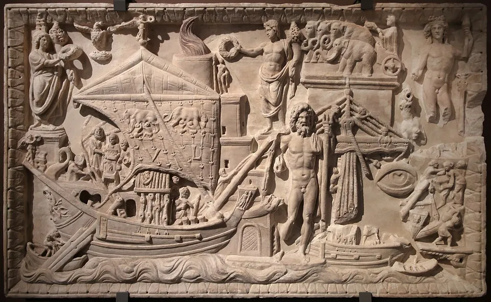 A crowded marble relief with a large sailing ship in the foreground, standing figures of gods, buildings and a tower topped by a flame behind it.