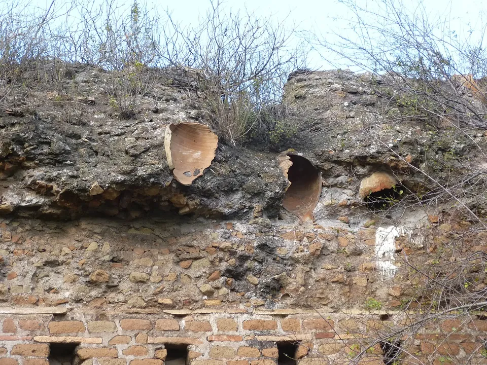 Broken clay jars embedded in a mass of mortar and rubble above a course of brickwork, their curved open sides facing outwards.