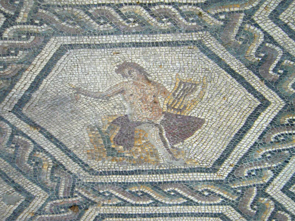 A mosaic panel framed by a hexagon and a band of twisted braid, showing a seated figure holding a lyre and stretching out one arm.