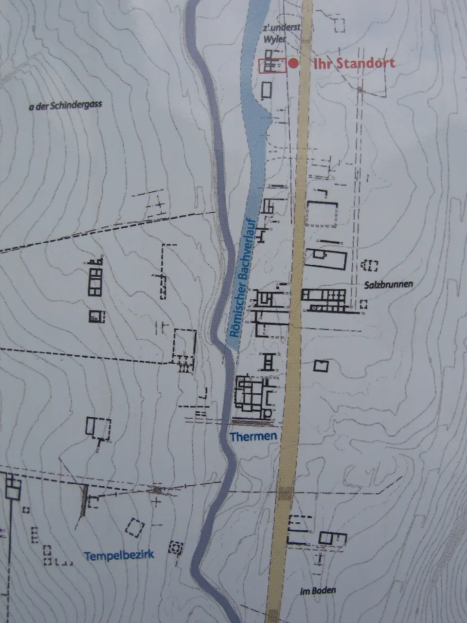 A plan board showing the Roman excavations along a stream, with the baths, the temple precinct, the Salzbrunnen area and a red "Ihr Standort" marker.
