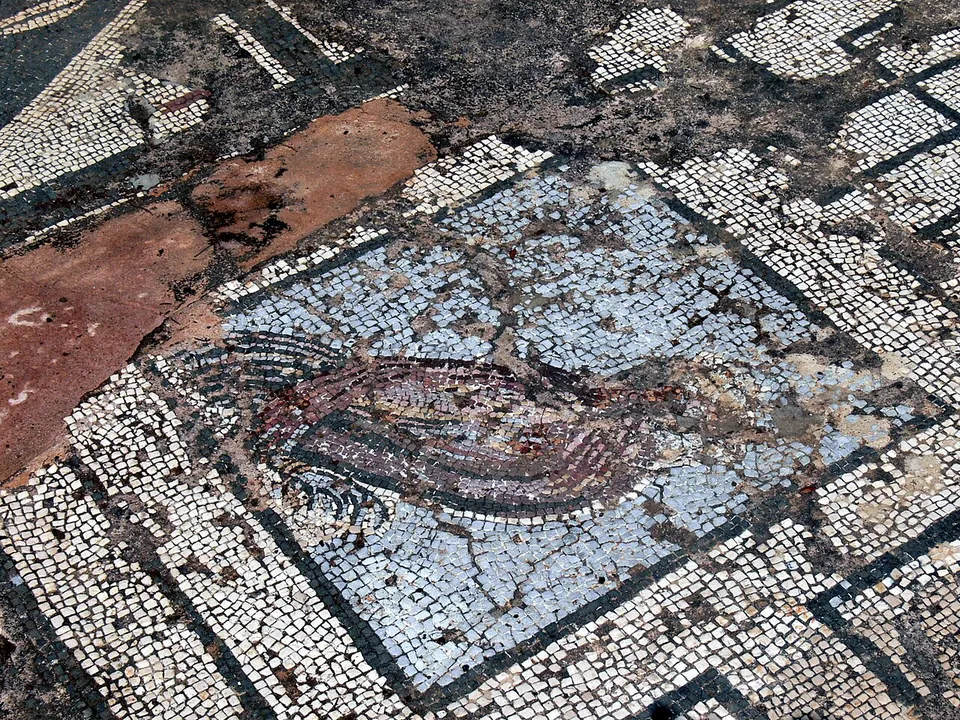 A mosaic floor of black and white squares framing a long-tailed bird picked out in red and dark stones on a pale ground.
