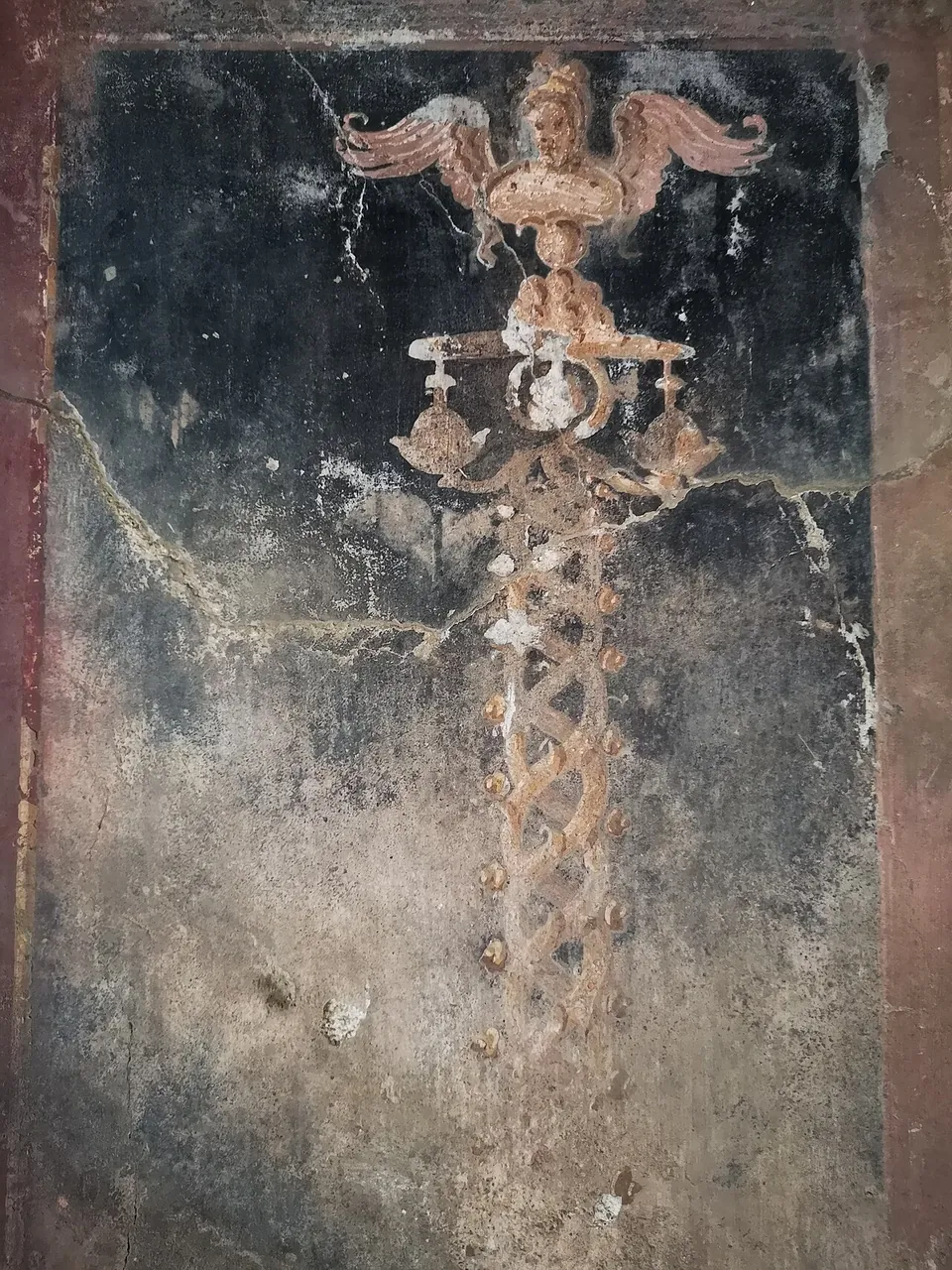 A black wall panel framed in red, on which a slender painted ornamental stem rises to a winged figure with outspread wings.