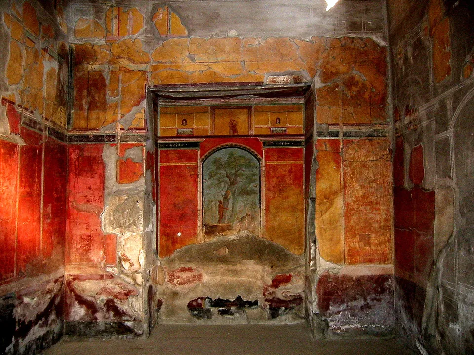 A room with walls painted deep red and ochre in framed panels; in a recess in the end wall, a central painted panel shows a tree in a garden scene.