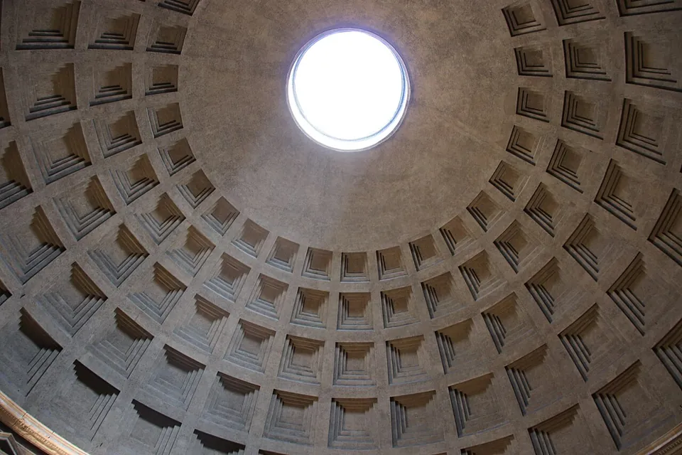 Looking straight up into the dome, rings of square sunken coffers narrowing towards a round opening at the top filled with bright sky.