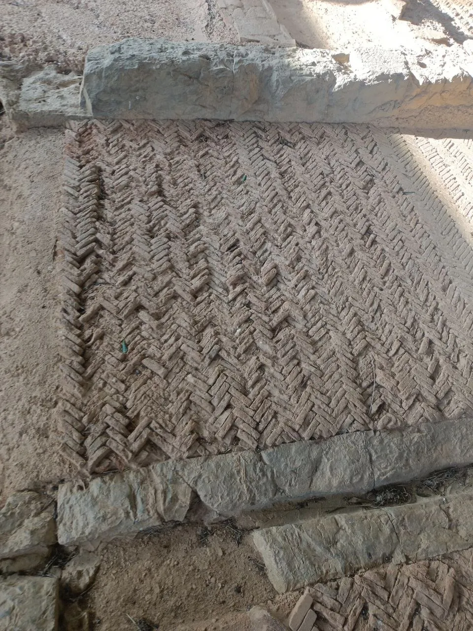 A floor of small bricks laid in a close herringbone pattern, edged by long stone slabs.