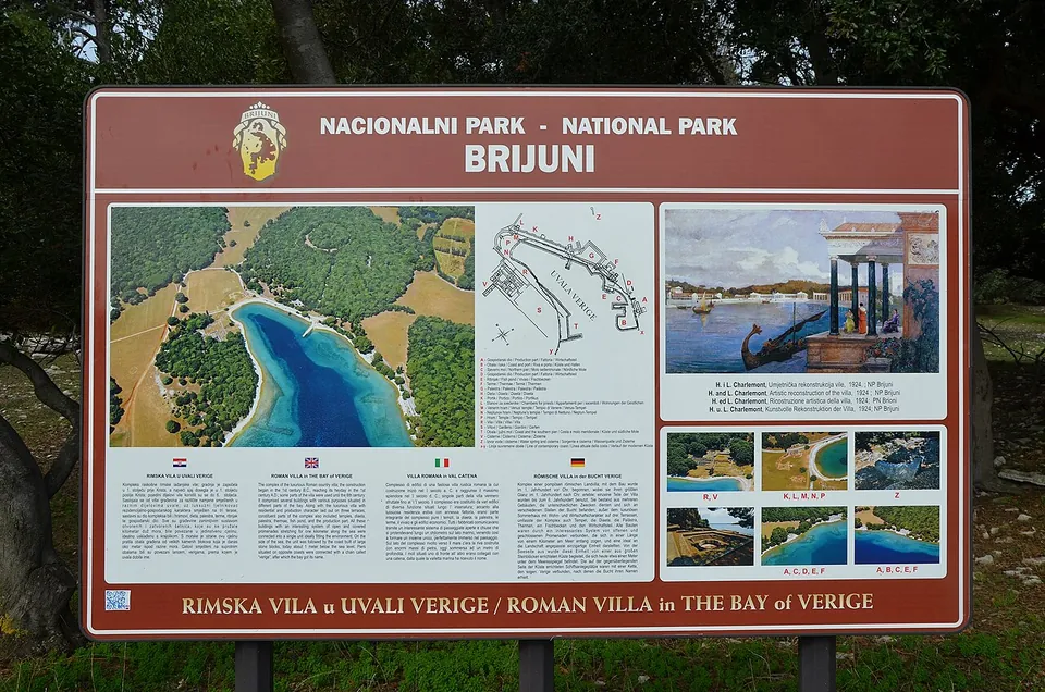 A brown national-park information board headed "Rimska vila u uvali Verige / Roman villa in the Bay of Verige", with an aerial photograph of the bay, a lettered plan of the complex, a painted reconstruction and text in Croatian, English, Italian and German.
