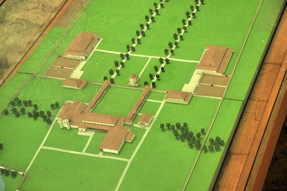 A model of the estate on a green board, a large walled rectangle with the main house at the bottom, smaller buildings along both sides and two avenues of trees leading away from the house.
