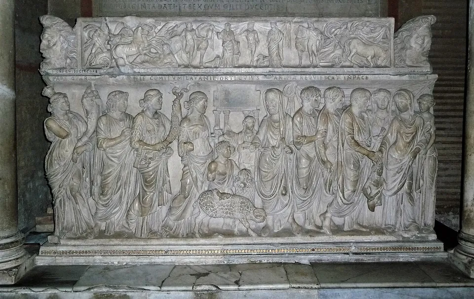 A marble sarcophagus carved along its whole front with a crowd of standing figures in long robes, among them a couple joining hands, and a lid carved with a frieze of smaller figures and masks at the corners.