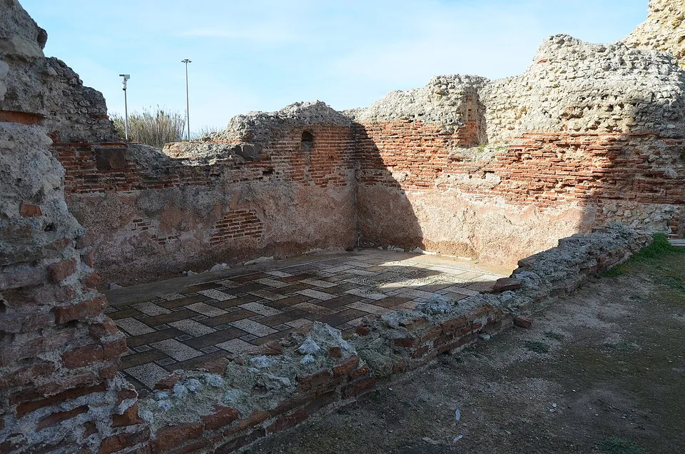 A sunken rectangular room walled in red brick, its floor laid with a chequered mosaic of light and dark squares.