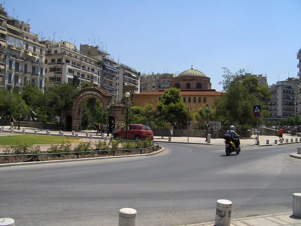 A domed church of brick and stone with a square drum and arched windows, seen among trees.
