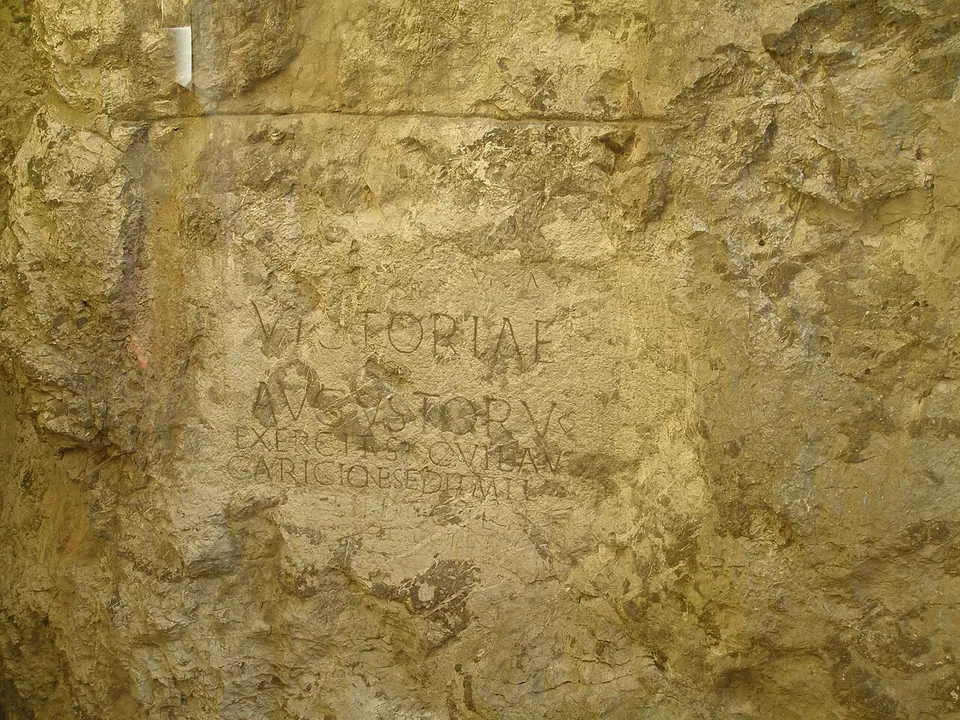 A smoothed, roughly rectangular panel cut into yellowish rock, with the large carved capitals VICTORIAE and AVGVSTORV at the top and smaller, more worn lines of lettering below.